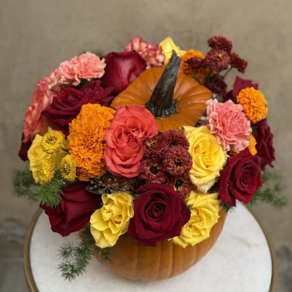 Pumpkin topped with red, yellow, and pink flowers