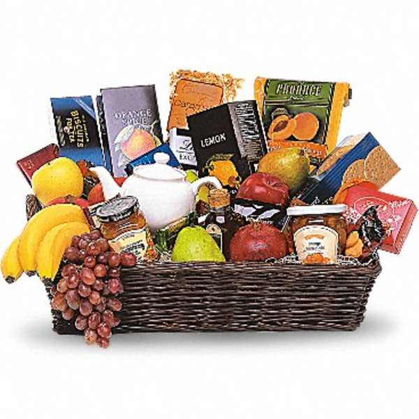 Gift basket with fruit, snacks, and a white teapot in a wicker tray