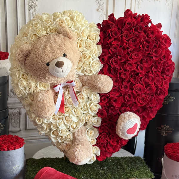 Heart-shaped rose arrangement with a teddy bear in the center