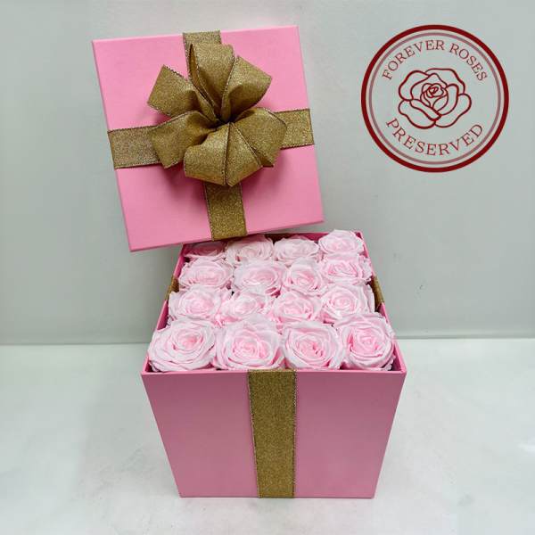 Pink gift box filled with pale pink roses and a gold ribbon bow