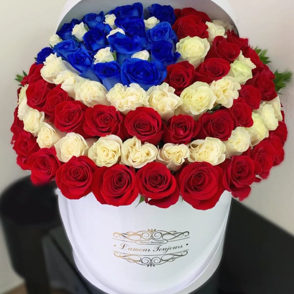 Round box arrangement of red, white, and blue roses