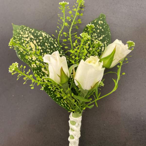 White rose boutonniere with speckled green leaves and ribbon wrap
