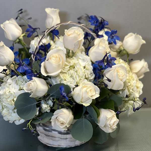 White roses and blue flowers in a white basket