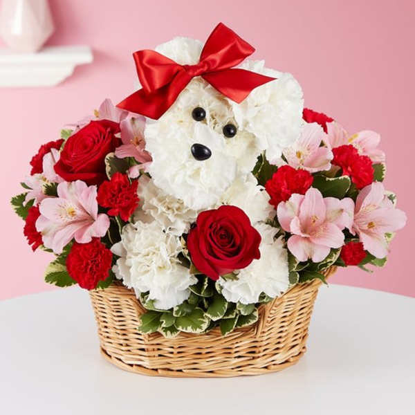 White teddy bear in a basket surrounded by red and pink flowers