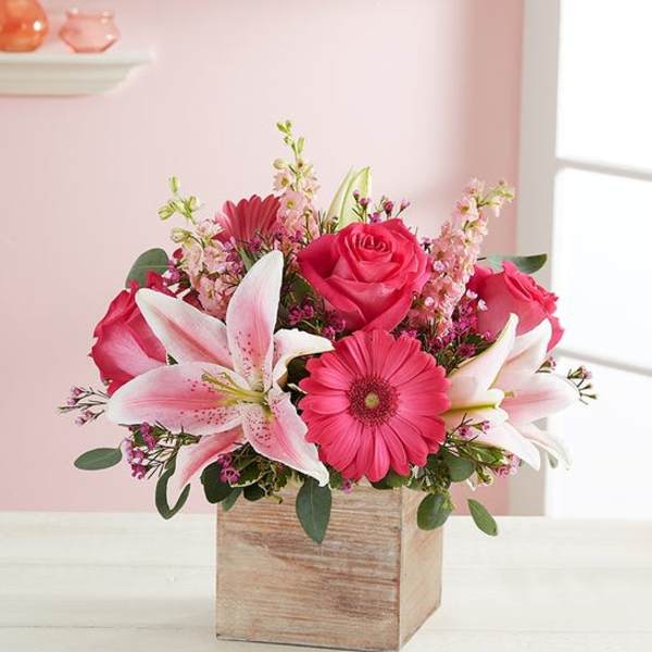 Pink roses and lilies arranged in a wooden box