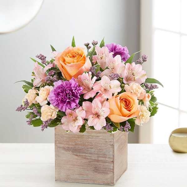 Peach and pink roses with purple carnations in a wooden box