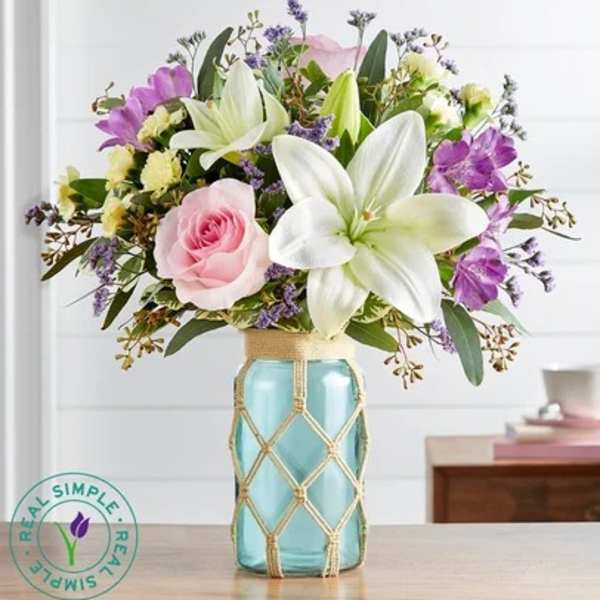 Pink rose and white lily bouquet in a blue glass vase