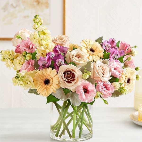 Mixed pastel flowers arranged in a clear glass vase