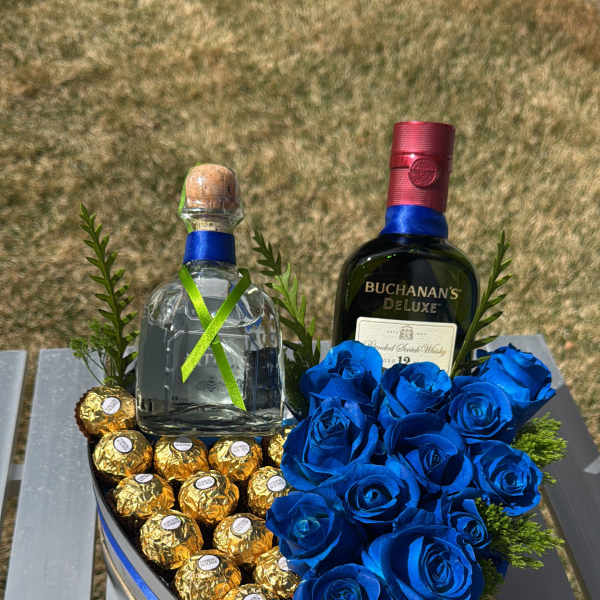 Heart-shaped gift box with blue roses, chocolates, and two liquor bottles