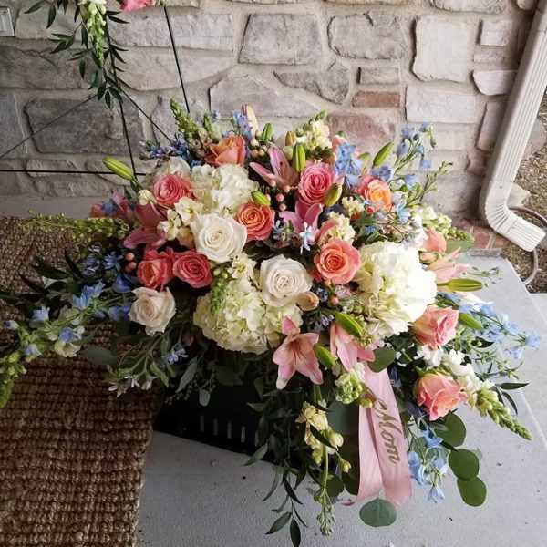 Large pastel floral arrangement with roses, lilies, and hydrangeas in a black container