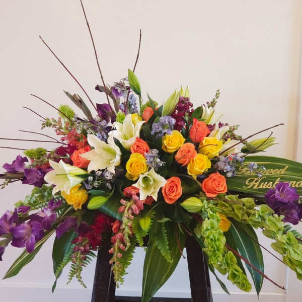 Large mixed bouquet with roses, lilies, and purple flowers in a low container