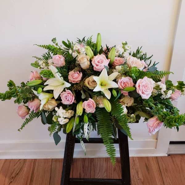 Pink roses and white lilies arranged in a low, wide display on a stand