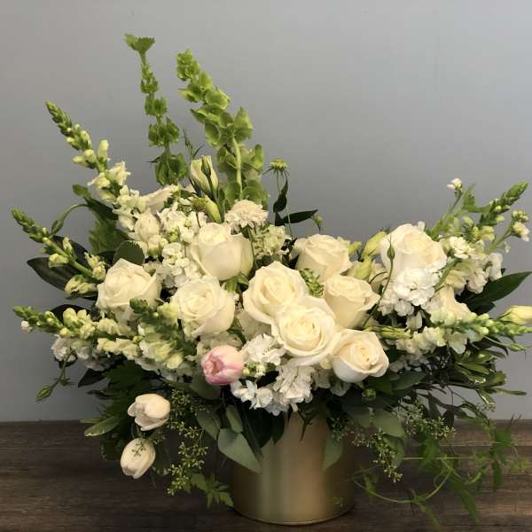 White rose arrangement with tall green spikes in a gold vase