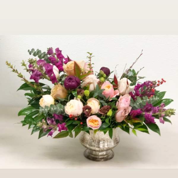 Mixed bouquet of pink, cream, and purple flowers in a silver vase