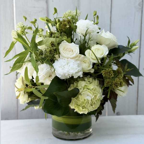 White roses and hydrangea arranged in a glass vase