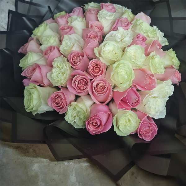 Bouquet of pink and white roses wrapped in black paper