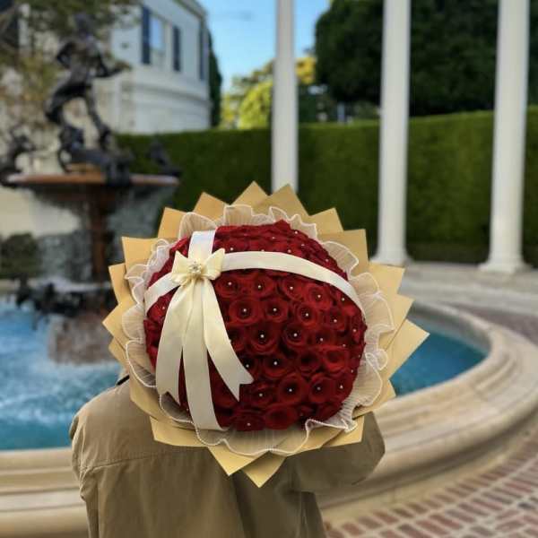 Round bouquet of red roses with a cream ribbon and tan wrap