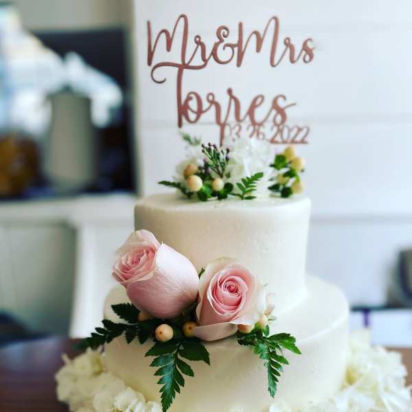 Two-tier white cake with pink roses and white flowers