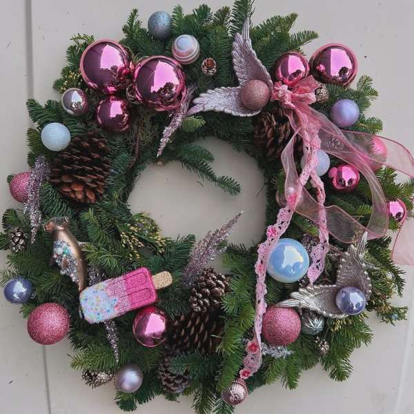 Christmas wreath with pink ornaments, pinecones, and ribbon