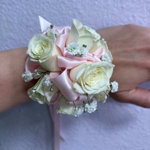 White rose wrist corsage with pink ribbon and small white filler flowers