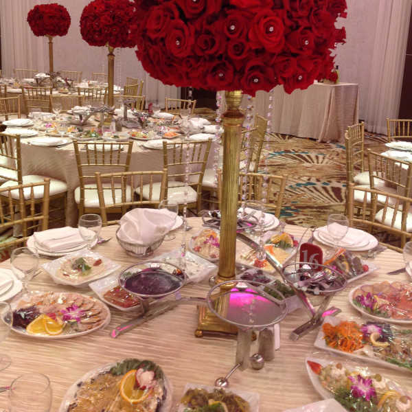 Large red rose centerpiece on a tall gold stand at a banquet table
