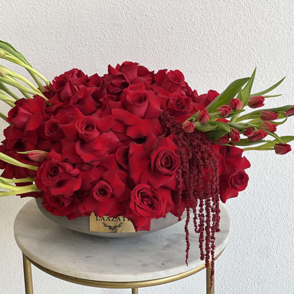 Large red rose arrangement with tulips in a low oval container
