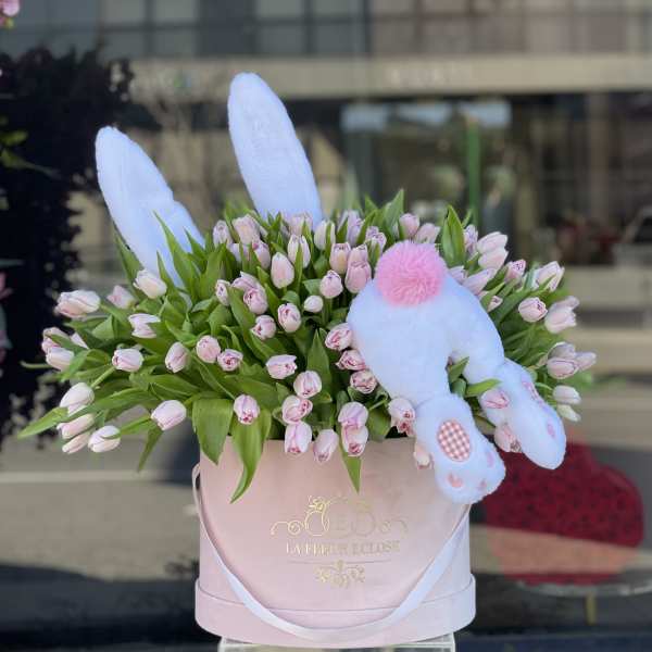 Pink tulips in a blush hatbox with a white plush bunny