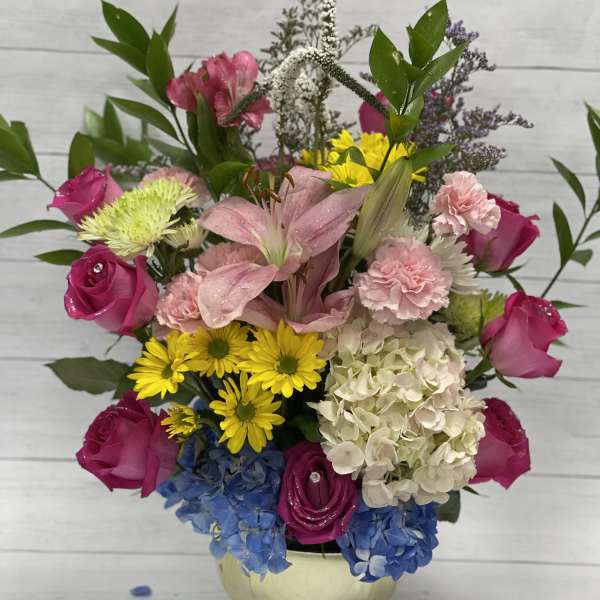 Mixed bouquet with pink roses, lilies, hydrangea, and yellow daisies in a vase