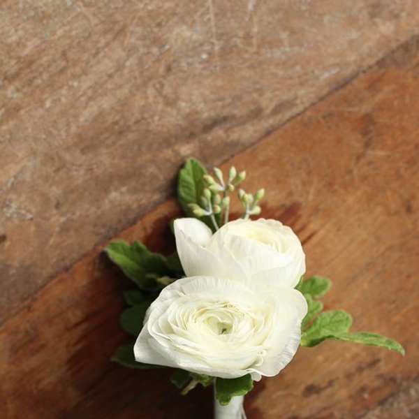 Small white flower boutonniere with green accents