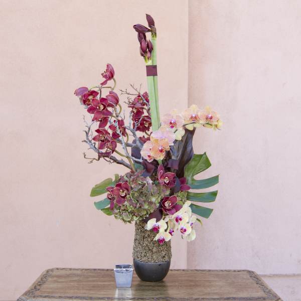 Tall orchid arrangement in a black vase with pink and white blooms