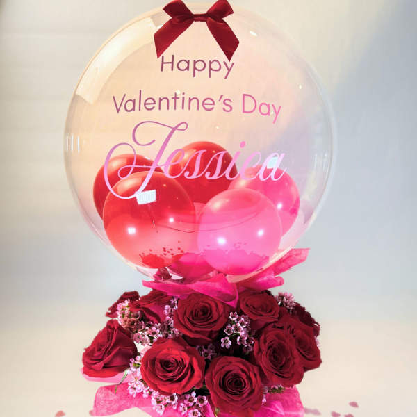 Red roses in a pink box with a clear balloon and Valentine’s Day message