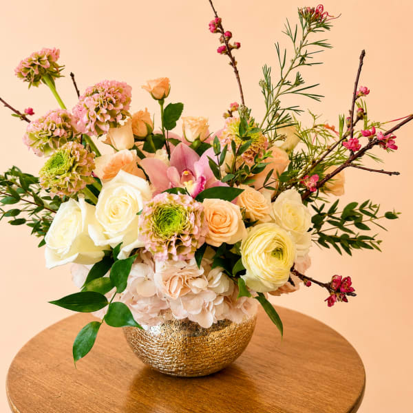 Mixed pastel flower arrangement in a gold bowl vase