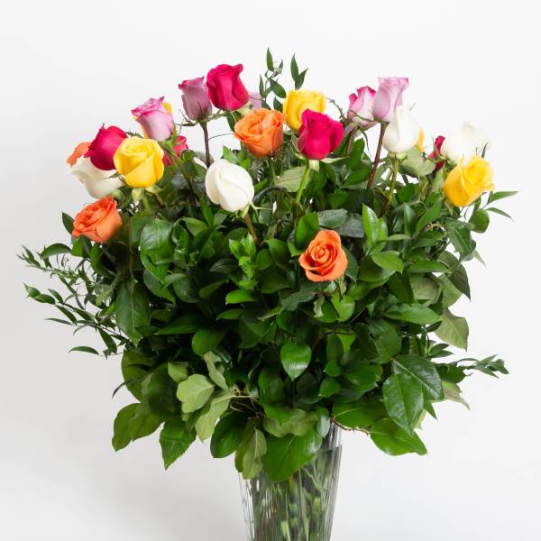 Mixed roses in a clear glass vase with dense greenery
