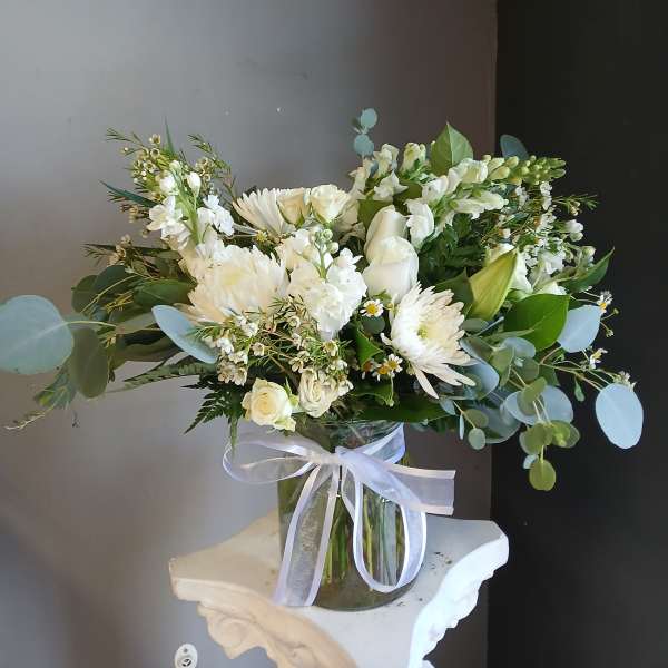 White bouquet in a glass vase with a white ribbon