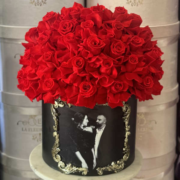 Red rose arrangement in a black decorative box with a framed couple photo