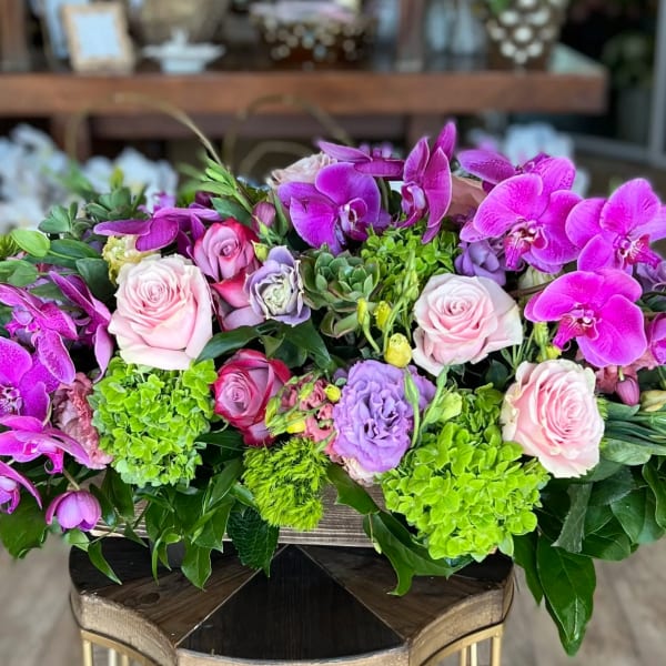 Pink roses and purple orchids in a low floral arrangement