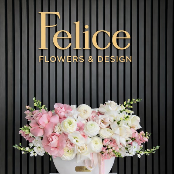 Pink and white floral arrangement in a white vase with a ribbon
