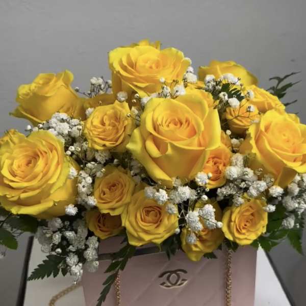 Yellow roses arranged in a pink gift box with baby's breath