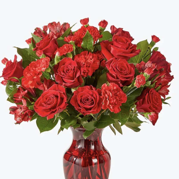 Red roses and carnations in a red glass vase