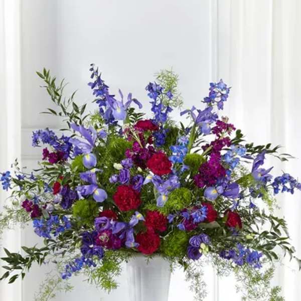 Large mixed floral arrangement in a white pedestal vase