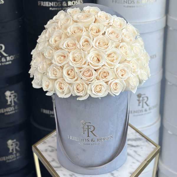 Cream roses arranged in a gray hat box