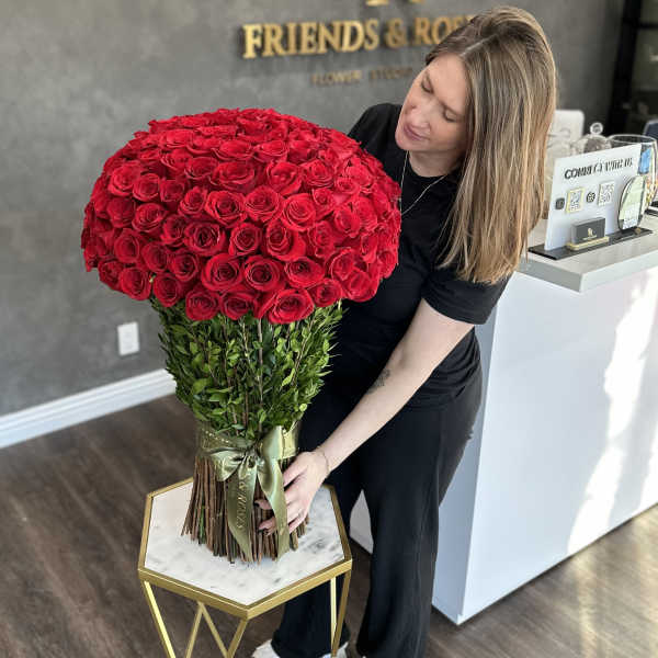 Large bouquet of red roses with a green ribbon, held by a woman
