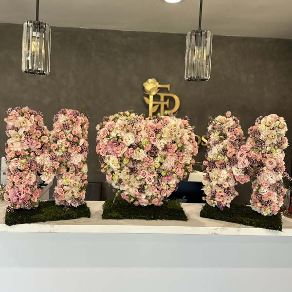 Floral letter arrangements spelling "MHD" in pink and white blooms