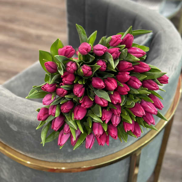 Bouquet of bright pink tulip buds with green leaves