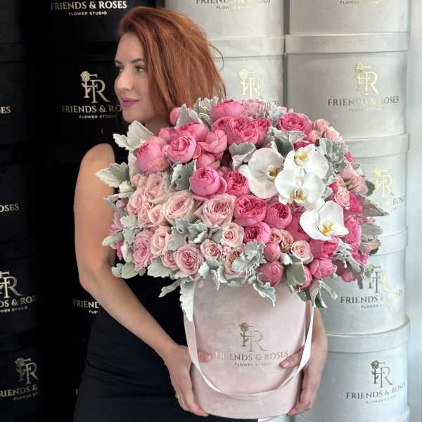 Woman holding a large pink rose bouquet in a round box