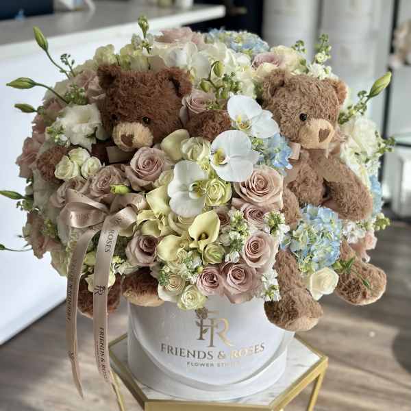 Bouquet of pastel roses, orchids, and teddy bears in a white hat box