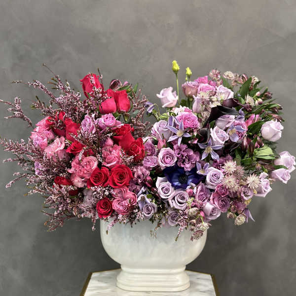 Large bouquet of pink, lavender, and red roses in a white vase