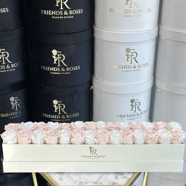 Box of pale pink and white roses in a branded hatbox