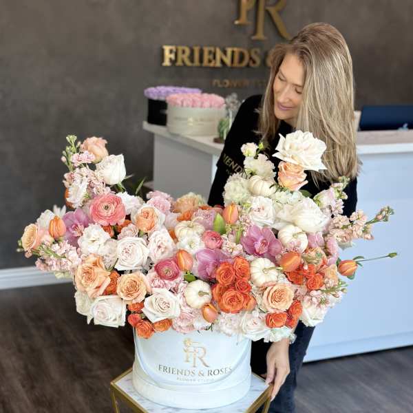 Large pastel flower arrangement in a white hat box with roses and orchids