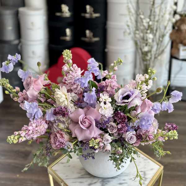Lavender and pink floral arrangement in a white bowl vase